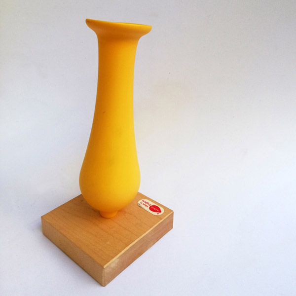 Yellow dip moulded plastic vase with wooden base.