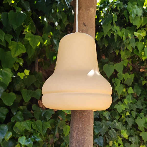 Yellow dip moulded plastic pendant light hanging from a tree. .