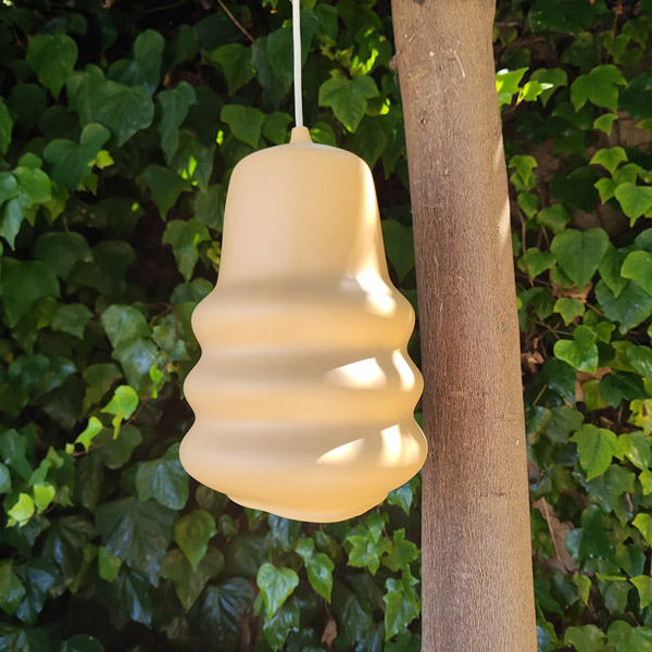 Yellow dip moulded plastic pendant light hanging from a tree.