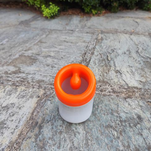 White ceramic toothbrush holder with red plastic top seen from above.