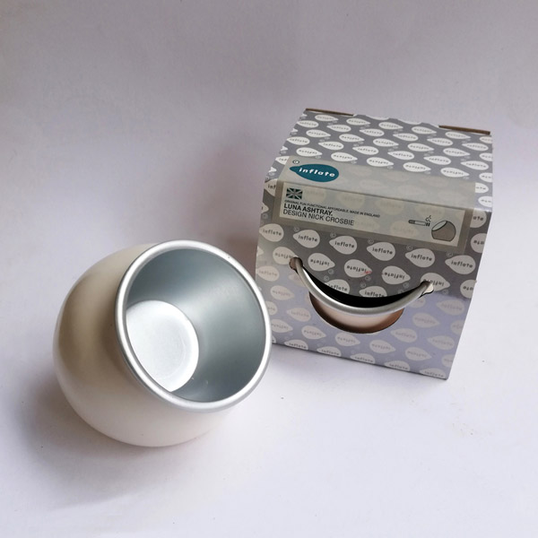 Metal ashtray in white plastic cover and paper packaging